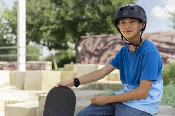 teenage boy with skateboard and helmet wearing vns therapy magnet on wrist