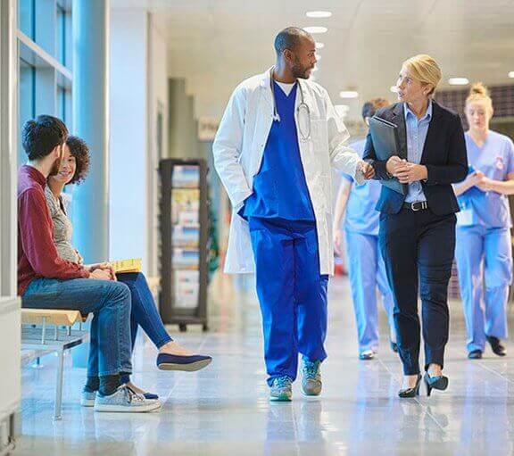 Doctor and business woman walking through a hospital