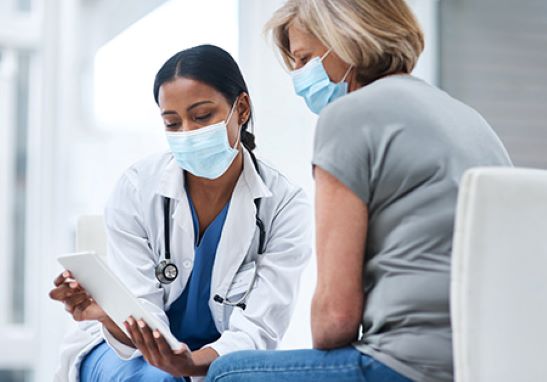 A healthcare professional showing a patient information while sitting down